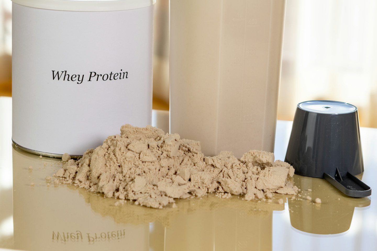 Molkenproteinpulver, Shake und Schaufel auf einer Arbeitsplatte.